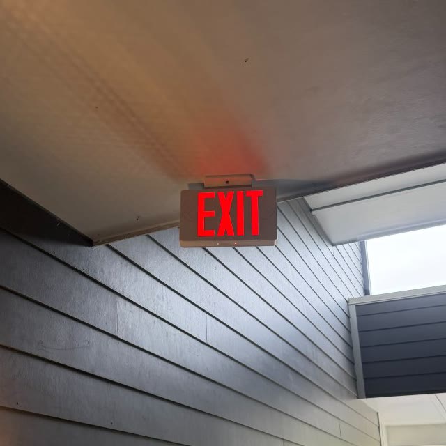 The exit sign secured to the breezeway ceiling and lit