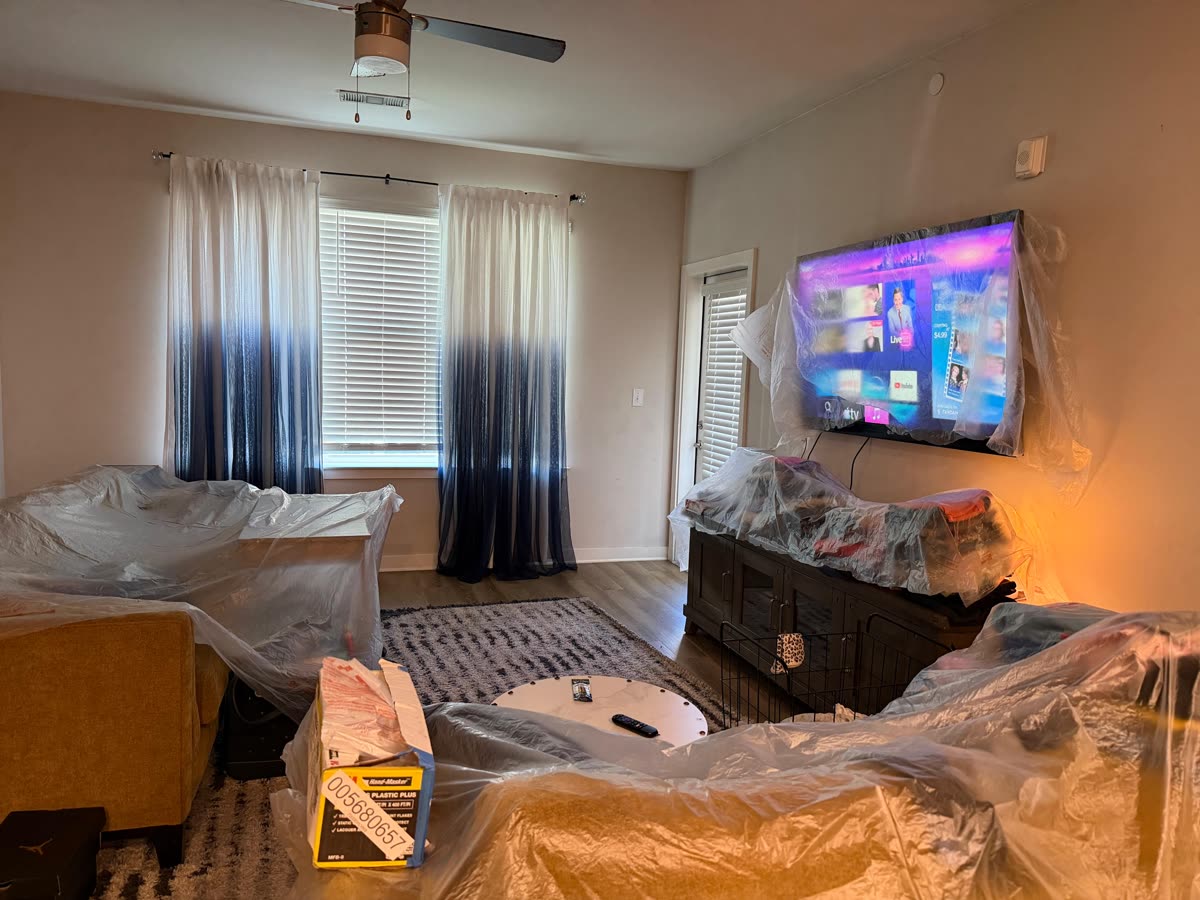 Living room with the sofas, TV stand and rug covered in plastic sheeting
