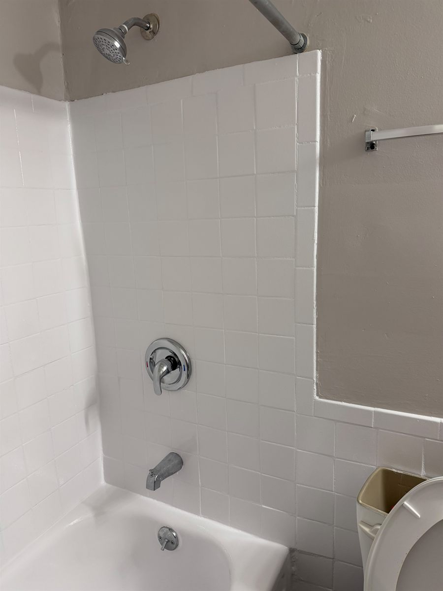 Refinished tub and tile surround beside a cleaned bathroom wall