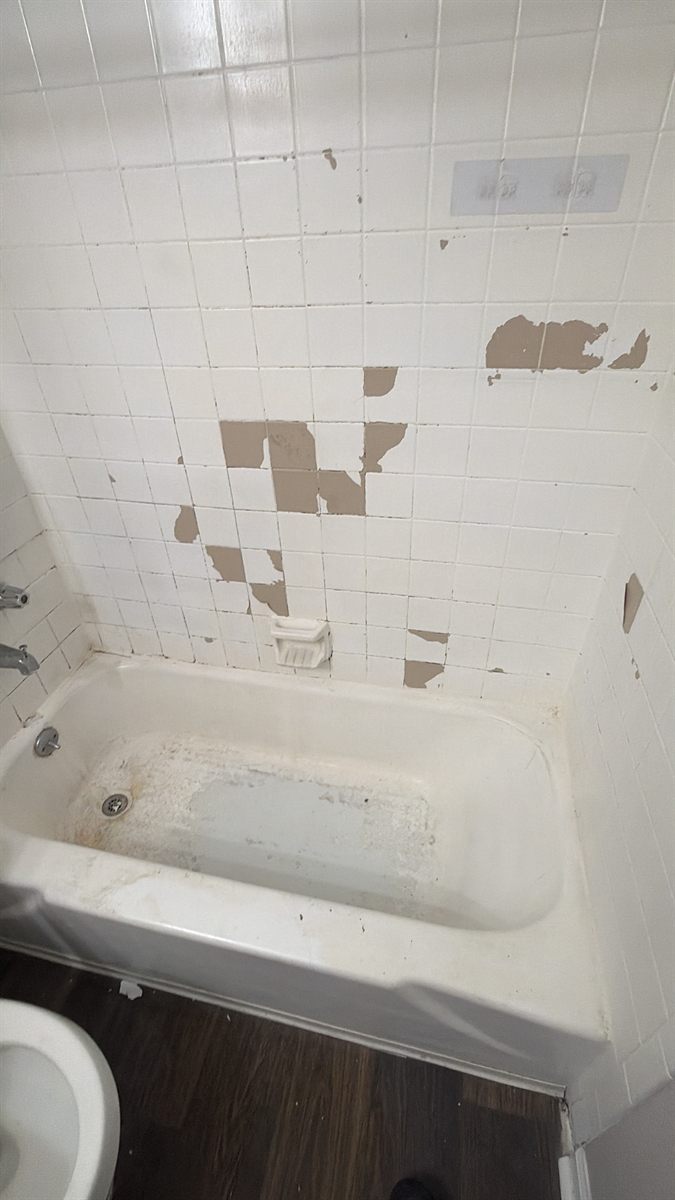 Tile surround with the glaze worn away in large patches before refinishing
